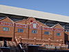 Brick facade of a stadium with a mosaic with a claret background and Aston Villa in gold writing.