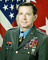 Portrait of a dark-haired white man wearing a military uniform with many ribbons, pins, and badges.