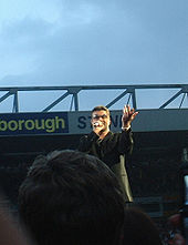 George Michael med Norwich and Peterborough Stand i baggrunden i juni 2007.  