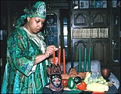 Žena zapaluje svíčky na stole s věcmi pro Kwanzaa  