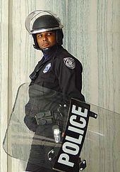Americký policista má na hlavě helmu a u sebe štít proti nepokojům. Říjen 2002