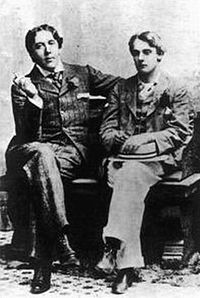 Zwei Männer in Anzügen sitzen mit gekreuzten Beinen auf einer Bank. Wilde und sein Geliebter, Lord Alfred Douglas, im Jahr 1893.
