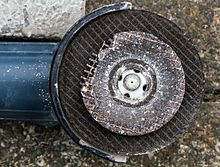 Worn cutting disc (front) of an angle grinder after freehand cutting of stone slabs (behind it the clamped unused tool)