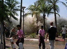 Tsunami que ocorreu em 2004 na Tailândia. A água da onda pode ser vista por trás das palmeiras ao fundo.