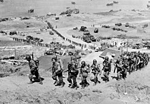 Shromažďování na pláži Omaha: posily mužů a techniky se přesouvají do vnitrozemí 7. června 1944