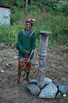 Man next to an Ai To'os in Watu, which correspond to a totem pole