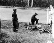 Francouzští civilisté pokládají květiny na tělo mrtvého amerického vojáka, 1944