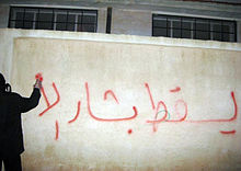 Syrský demonstrant sprejuje graffiti proti Bašáru Asadovi během arabského jara v Sýrii.