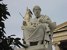 Plato and Athena in the background, in front of the Academy of Athens.