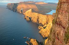 While the western coasts of the islands are often steep and inaccessible, the land slopes flatly towards the east; it is there in the bays that most Faroese live. View from the cliff Beinisvørð to the north.