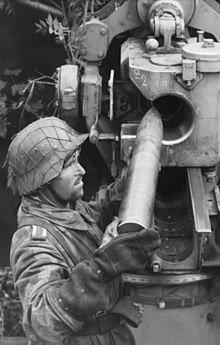 Deutscher Artillerist, der eine Patrone in eine 8,8 cm Flak 36 oder 37 lädt