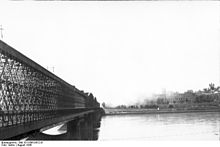 Billede af oprøret taget fra den modsatte side af floden Vistula. Kierbedź-broen set fra Praga-kvarteret mod kongeslottet og den brændende gamle bydel.