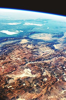 Andesbergenas högslätter (3000-5000 m) ligger i förgrunden. Salar de Arizaro (i förgrunden) är den största av de torra sjöarna i denna vy. Nära mitten utgör de två zonerna, Puna och Sierras Pampeanas, en slående kontrast. Sierras Pampeanas-bergen är lägre och har färre unga vulkaner.