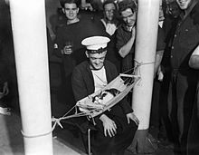 O comboio dorme em uma rede a bordo da HMS Hermione, enquanto os membros da tripulação observam