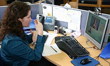 En døv person på arbejdspladsen, der kommunikerer med en hørende person ved hjælp af en video relay service. Hun bruger tegnsprog, som operatøren oversætter højt for den hørende person.  