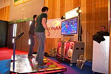 Spillere bruger en dansemåtte til at spille Dance Dance Revolution, et af de mest succesfulde rytmespil.