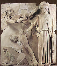 Herakles bryter ett hål i stallets grund med en kofot medan Athena pekar på platsen med sitt spjut i en metop från Zeustemplet i Olympia.  