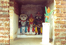 Jagannatha (black) with his siblings Balabhadra (white) and Shubhadra (yellow) in a village temple in Odisha. In the foreground in worship pose Garuda, the companion bird of Vishnu.