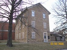 El Museo del Antiguo Castillo, el primer edificio construido para la Universidad de Baker. A la derecha hay una réplica de la Cabaña Kibbee.  