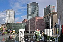 View of the center of Dortmund. From left to right: IWO high-rise, City and State Library, RWE Tower, Dortberghaus, Sparkassen high-rise. In the foreground the Platz der Deutschen Einheit at the German Football Museum.