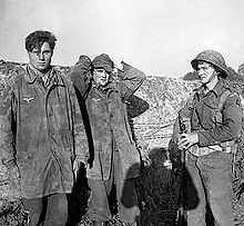An Allied soldier guards two German prisoners of war near Caen, July 11, 1944.