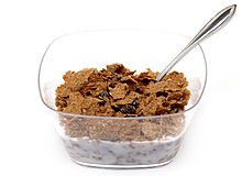 Miska cereálií Raisin Bran v průhledné plastové misce a nízkotučné mléko. Jedná se o dobrý příklad nízkotučných potravin.  