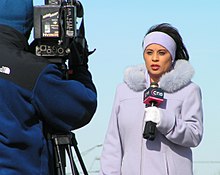 Telereporter, kes hoiab mikrofoni.