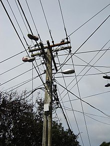 Mast, der bærer telefon-, el- og kabel-tv-udstyr. To par sko kan ses hængende i ledningerne.