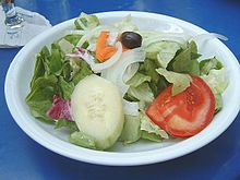 Piring dengan salad hijau, bawang bombai, tomat, mentimun, wortel dan zaitun hitam