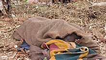 Contadino del Burundi che dorme sotto una coperta.