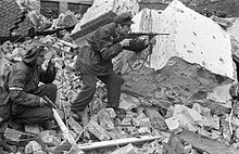 Henryk Ożarek "Henio" (til venstre) og Tadeusz Przybyszewski "Roma" (til højre) fra "Anna"-kompagniet i "Gustaw"-bataljonen i området omkring Kredytowa-Królewska-gaden. "Henio" holder en Vis-pistol, og "Roma" affyrer en Błyskawica-maskinpistol. 3. oktober 1944