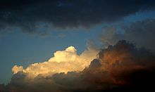 Only the highest parts of the clouds are still illuminated by the setting sun.