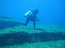 Ein Taucher, der auf dem gigantischen Yonaguni-Felsen unter Wasser geht.