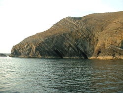 Los estratos son las capas de roca, originalmente dispuestas de forma horizontal. Esto es de Trwyn y Fulfran, Lleyn, Gales.