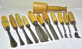 Una selezione di utensili manuali per l'intaglio del legno: 3 sgorbia a coda di pesce, un attrezzo a V, 4 sgorbia diritta, 3 sgorbia a cucchiaio e un martello da intagliatore