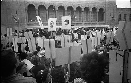 Protesters at the DNC hold signs showing the three murdered Freedom Summer activists