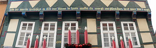 Inschrift in Mittelniederdeutsch an einem Haus in Hameln. - "Alle der warlde herlicheyt is alse ene ene blome de huete wasset un morgen vorgheit. Des herrn wort blift yn ewicheit" - Übersetzung: Die ganze Pracht der Welt ist wie eine Blume, die heute wächst und morgen verschwindet; das Wort des Herrn bleibt in der Ewigkeit.