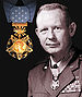 Head and shoulders of a white man with a half-smile and short hair, wearing a military jacket with rows of ribbon bars on the left breast and a star-shaped medal hanging from a ribbon around his neck. A depiction of the same medal, gold with a blue ribbon, is in the upper left of the image.