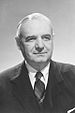 Head and shoulders of an older man with neatly combed and parted gray hair wearing a suit and tie.