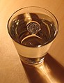 Surface tension prevents a coin from sinking: the coin is indisputably denser than water, so it must be displacing a volume greater than its own for buoyancy to balance mass.