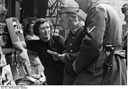 Questo è un tipo di interazione molto più complesso. Soldati tedeschi parlano con una donna francese in Lorena, Francia, novembre 1940.