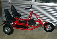 Tandem trike with one couple of handlebars and pedals for two people