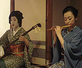 Two geisha playing the shamisen and the shinobue.