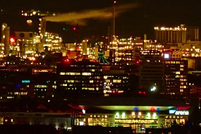 The water tower with green glowing stripes on its roof in the center of the picture with the SAP Arena placed 3.8 km in front of it and the bright industrial background of Ludwigshafen is easily visible with the perspective from 20.8 km away in Heidelberg with 12 x 60 binoculars
