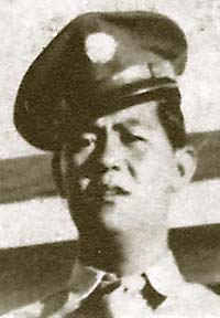 The head and shoulders of a young man in his Army dress uniform. He is standing and staring forward towards the camera with his hat cocked to the side.