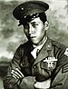 Head and shoulders of a young man wearing a peaked cap and a military jacket with ribbon bars and a badge on the left breast.