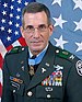 A color image of Roberts wearing his Army Green Uniform. There is an American flag and a Medal of Honor flag in the background.