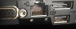 Hardware interfaces on the side of a laptop computer (from left): VGA monitor port, network port (center), Display Port monitor port (top right), USB 2.0 (bottom right).