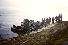 Brytyjscy Królewscy Marines wysiadają z lądownika Rigid Raider na plaży podczas ćwiczeń.