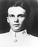 Head of a young, dark-haired man in a white military coat with bright buttons and an emblem on the collar.